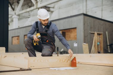 Marangoz fabrikadaki modüler yapı için kablosuz tornavida kullanarak prefabrik ahşap paneller monte ediyor.