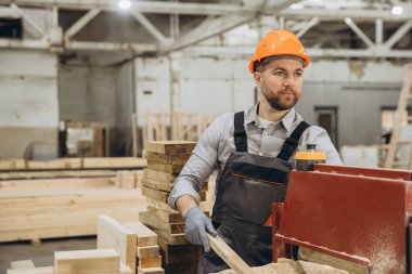 Fabrika atölyesinde talaş, alet ve teçhizatla ahşap ustası bir marangoz. İnşaat endüstrisindeki zanaatkarlığı gösteriyor