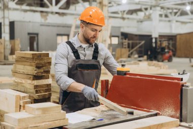Marangoz, prefabrik ev üretimi için bir fabrikada testere makinesi kullanarak tahta kesiyor.