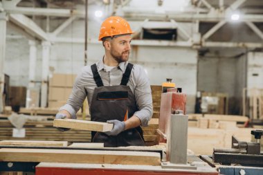 Bir fabrikadaki marangoz modern teknoloji ve makine kullanarak hassas ve çevre dostu uygulamalarla modüler binalar için ahşap işçiliği yapıyor.