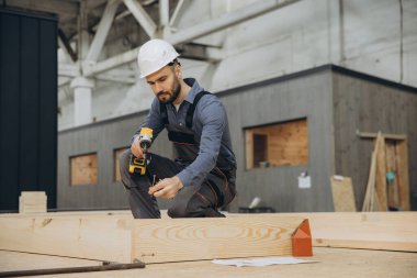 Marangoz, kablosuz tornavida ve vida kullanarak modüler yapı fabrikasında prefabrik ev bölümünü monte ediyor.