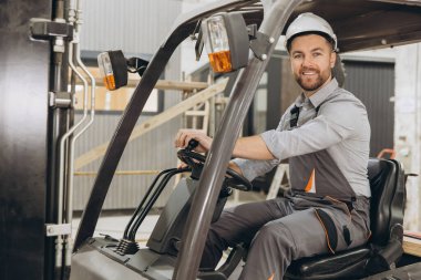 Kendine güvenen bir depo işçisi, yoğun bir fabrikada forklift kullanıyor. Verimli ulaşım ve malzemelerin güvenli şekilde kullanılması sağlanıyor.
