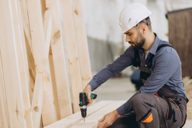 Marangoz, büyük marangozluk atölyesinde modüler yapı için kablosuz matkap ve ahşap çerçeve kullanıyor.