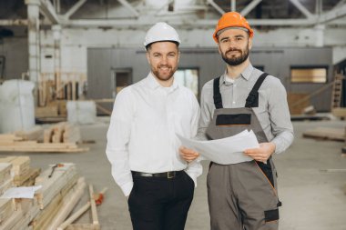 Modüler bir inşaat fabrikasındaki prefabrik konutların planlarını inceleyen mimar ve müteahhit, kalite ve hassasiyeti garanti altına alıyor.