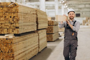 İnşaat için kereste taşıyan yetenekli bir marangoz. Sanayide işçilik ve profesyonellik gösterisi yapıyor. Yapı projeleri için odun üretimi ve depolamaya odaklanın