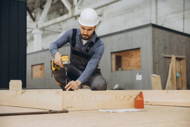 Marangoz, modüler yapı yapımında kablosuz tornavida kullanarak bir fabrikada prefabrik ahşap parçalar monte ediyor.