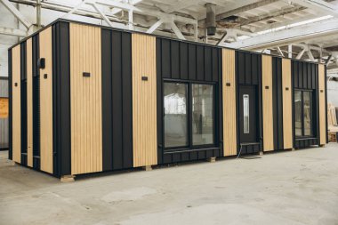 Modern prefabricated tiny house being built inside a spacious factory, showcasing innovative construction techniques clipart