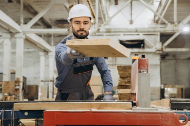 Marangoz bir fabrikada ahşap bir kalas taşıyordu. Modüler inşaat endüstrisine hassasiyet ve uzmanlıkla katkıda bulunuyordu.
