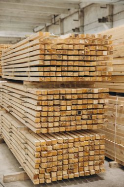 Büyük bir kereste deposunda modüler yapı inşaatı için istiflenmiş ve hazır olan yapıştırılmış kereste kalasları.