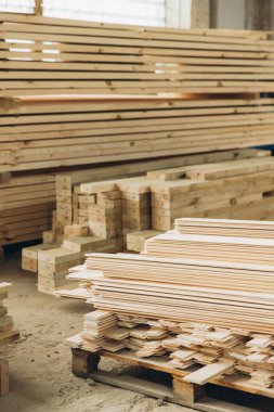 Ahşap bir fabrikada düzgün istiflenmiş tahta ve tahtalar, modüler yapı inşaatı için hazır.