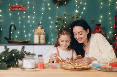 Anne ve kızı mutfakta zencefilli kurabiye süslüyor, Noel 'in tadını çıkarıyorlar.