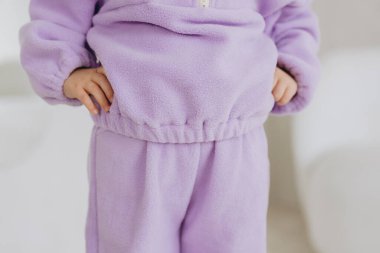 Rahat bir mor yün eşofman giyen, yumuşak dokusunu ve giysisine uyan bir çocuğun yakın çekimi.