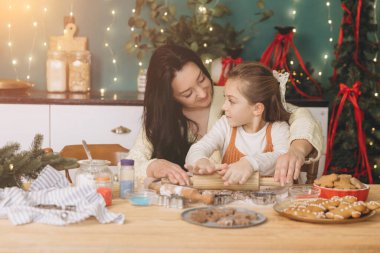 Anne kızına Noel kurabiyeleri pişirmeyi öğretiyor. Dekorasyonlu mutfaklarında iç açıcı bir tatil anı yaratıyor.