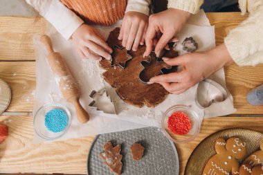 Anne ve kızı noel kurabiyelerini hazırlarken yıldız ve zencefilli kurabiye şekilli kurabiye kesicileri kullanıyorlar.