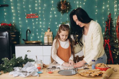 Anne ve kızı, Noel kurabiyelerini birlikte güzel dekore edilmiş mutfaklarında pişiriyorlar. Tatil geleneklerinin sıcaklığını kucaklıyorlar.