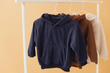 Giysi askısına asılmış çeşitli renklerde kapüşonlu kapüşonlu çocuklar moda markası için minimalist bir model sunar.