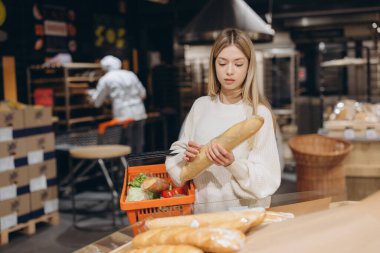 Marketin fırın bölümünden ekmek toplayan genç bir kadın.