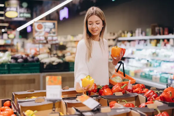 Marketten taze dolmalık biber seçen genç bir kadın.