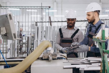 Modern bir üretim hattında alüminyum ve PVC pencere ve kapılarını birleştirirken işbirliği yapan iki fabrika işçisi