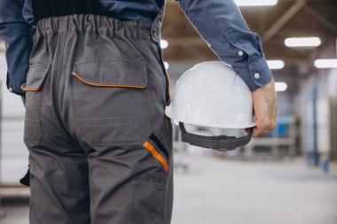 Modern bir alüminyum ve PVC pencere ve kapı üretim fabrikasının içinde elinde beyaz başlık tutan inşaat işçisi