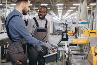 Üniformalı iki fabrika işçisi modern endüstriyel üretim fabrikasında alüminyum ve pvc pencere ve kapılar için bir makine çalıştırıyorlar.