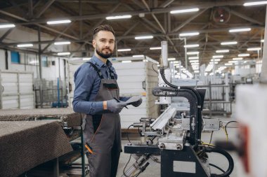 Fabrika işçisi panoya notlar yazarken alüminyum ve pvc pencere ve kapı üretiminde kullanılan endüstriyel makineleri kontrol ediyor