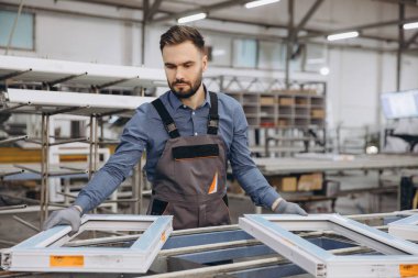 Modern bir tesiste üretim hattı boyunca PVC pencereleri monte eden fabrika işçisi, kaliteli işçilik için gelişmiş makineler ve teknoloji kullanıyor