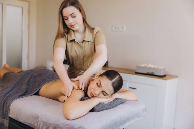 Profesyonel masöz, sağlık merkezindeki genç bayana sırt masajı yapıyor.