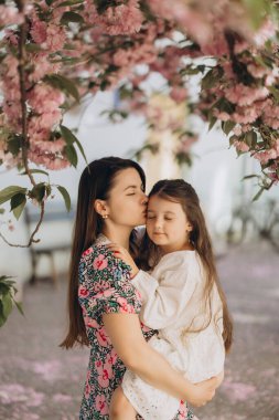 Anne kızını alnından öpüyor. Büyüleyici bir sakura ağacının altında. Çiçek açmış, ilkbaharda aşkı ve birlikteliği kutluyor.
