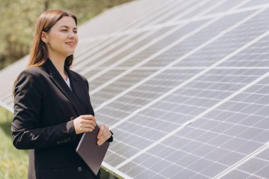 Güneş enerjisi, yenilenebilir enerji ve yeşil ekonomi kavramı, güneş panellerini incelerken elinde tablet ve gülümseyen iş kadını