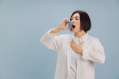 Solunum krizi sırasında mavi astım spreyi kullanan olgun bir kadın. İlk yardım ve önleme kavramı.