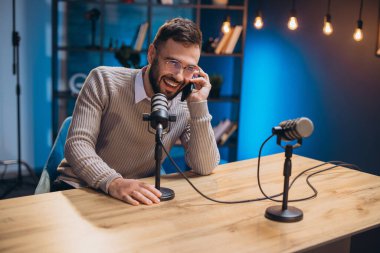 Modern bir ev stüdyosunda bir ses podcast 'i kaydederken, yaratıcılık ve coşku içeren mutlu podcaster.