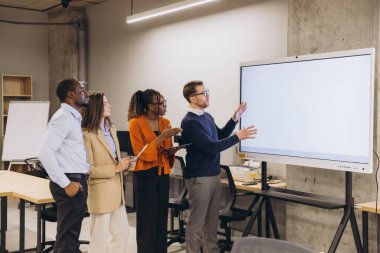 Dijital ekranın yanında işbirliği yapan çeşitli profesyoneller, çağdaş iş ortamında kurumsal toplantılarda görüşlerini paylaşıyorlar.