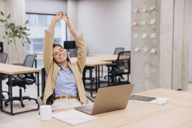 Profesyonel iş kadını yönetici esneme, ergonomik sandalyeye yaslanma çağdaş çalışma alanındaki dizüstü bilgisayar işini tamamladıktan sonra