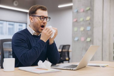 Ofiste çalışırken burnunu mendile sümküren iş adamı soğuk algınlığı ya da alerjiden muzdarip.