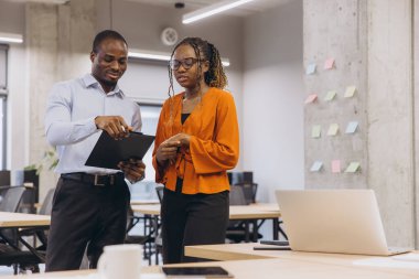 Proje detaylarını pano ile analiz eden iş adamları, çağdaş çalışma alanındaki yapışkan notlar