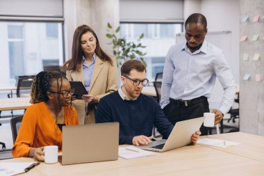 Çağdaş bir ofis ortamında birlikte çalışan profesyonellerden oluşan bir grup, iş amaçlarına ulaşmak için takım çalışması ve işbirliğine odaklanıyor.