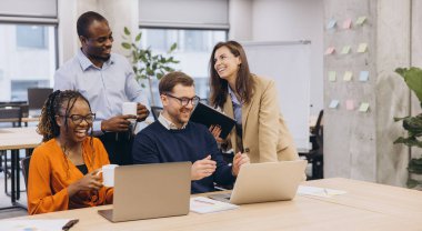 Günümüz iş ortamında laptoplar, takım çalışması ve çeşitliliğini gösteren canlı bir tartışma içine giren bir grup profesyonel.
