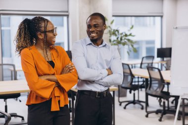 Kurumsal Afro-Amerikalı meslektaşlar işbirliği yapıyor, modern çalışma alanında birlikte çalışırken olumlu ifadeler veriyorlar, profesyonel sinerjiyi temsil ediyorlar.