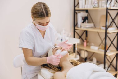 Spa ortamındaki yetenekli güzellik uzmanları, cilt bakımına ve gençleştirme tekniklerine odaklanan müşterilere yüz bakımı sağlar.