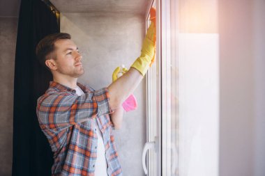 Kapıcı pencereleri deterjan ve mikrofiber bezle temizliyor, ev temizliği, temizlik ve hijyen konseptiyle temizliyor.