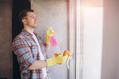 Eldiven giyen hademe, pencereyi sprey şişesi ve mikrofiber bez ile temizliyor. Kapalı alanda temiz ve temiz bir son sağlıyor.