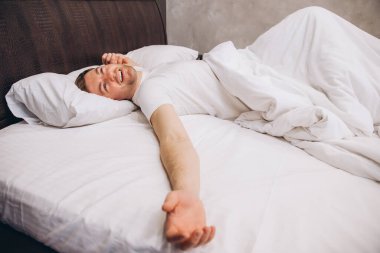 Genç adam mışıl mışıl uyuyor. Huzurlu ve huzurlu bir uykudan zevk alıyor. Rahatlamayı ve sağlıklı uyku alışkanlıklarını temsil ediyor.