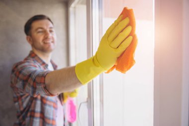 Gülümseyen adam bir bez ve eldivenle pencereyi dikkatlice temizler, pırıl pırıl ve temiz bir son garantiler.