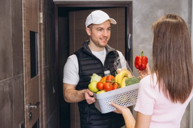Kurye, kapısının önünde müşteriye taze yiyecek getiriyor. Uygun ve verimli bir yemek servisi sunuyor.