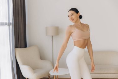 Oturma odasında yoga yapan sağlıklı bir kadın, sağlıklı bir yaşam tarzının ve iç huzurunun tadını çıkarıyor.