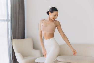 Evde yoga yapan sağlıklı bir kadın, huzurlu ve huzurlu bir atmosferin tadını çıkarırken, sağlık ve sağlığını da geliştiriyor.