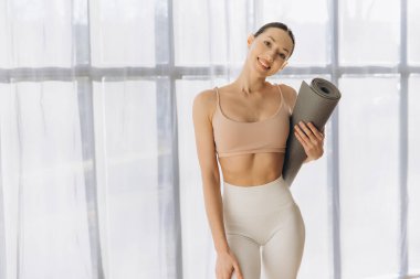 Gülümseyen kadın yoga minderini tutuyor evde egzersiz yapmaya hazırlanıyor, sağlıklı yaşam tarzı ve sağlık konsepti.