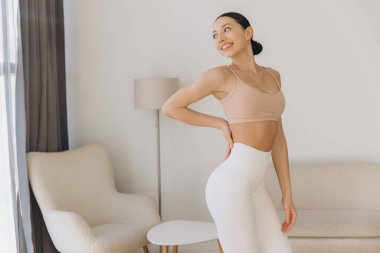 Oturma odasında yoga yapan sağlıklı bir kadın huzurlu ve dengeli bir yaşam tarzının tadını çıkarırken sağlığını ve sağlığını kucaklıyor.