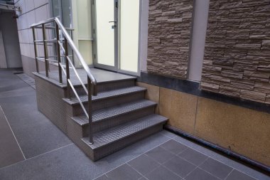 Gri çelik plaka ve paslanmaz çelik parmaklıklardan yapılmış merdiven.